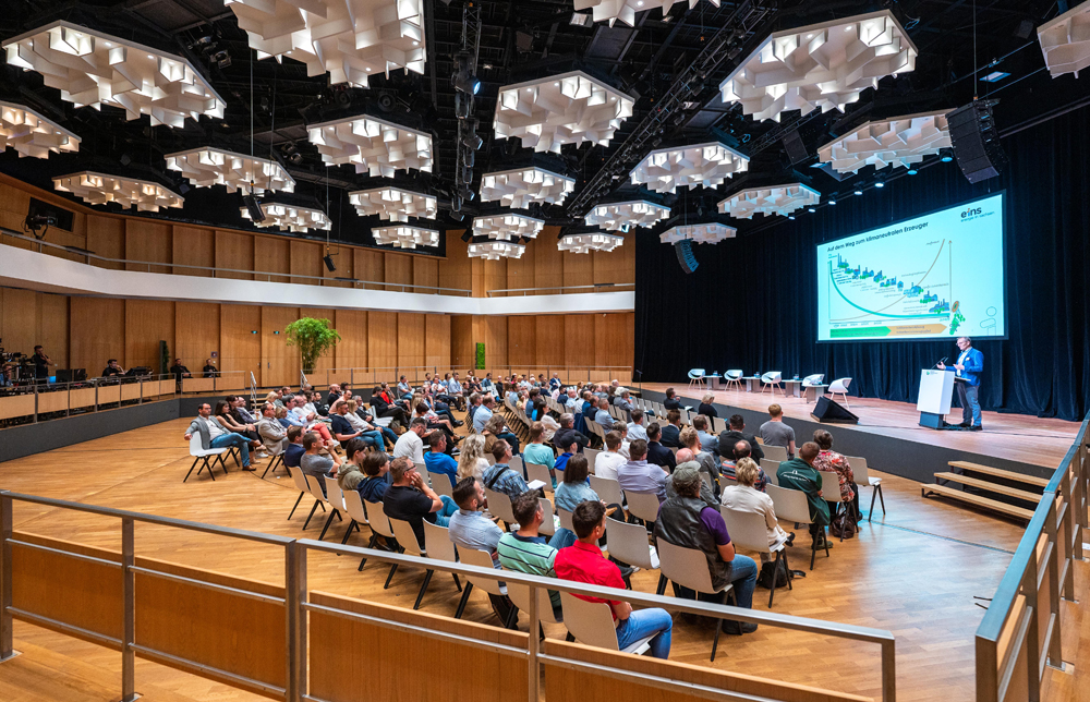 Roland Warner hält ein Vortrag dazu, ein klimaneutraler Erzeuger zu werden. Vor ihm sitzen viele Leute in einer großen Konferenzhalle.