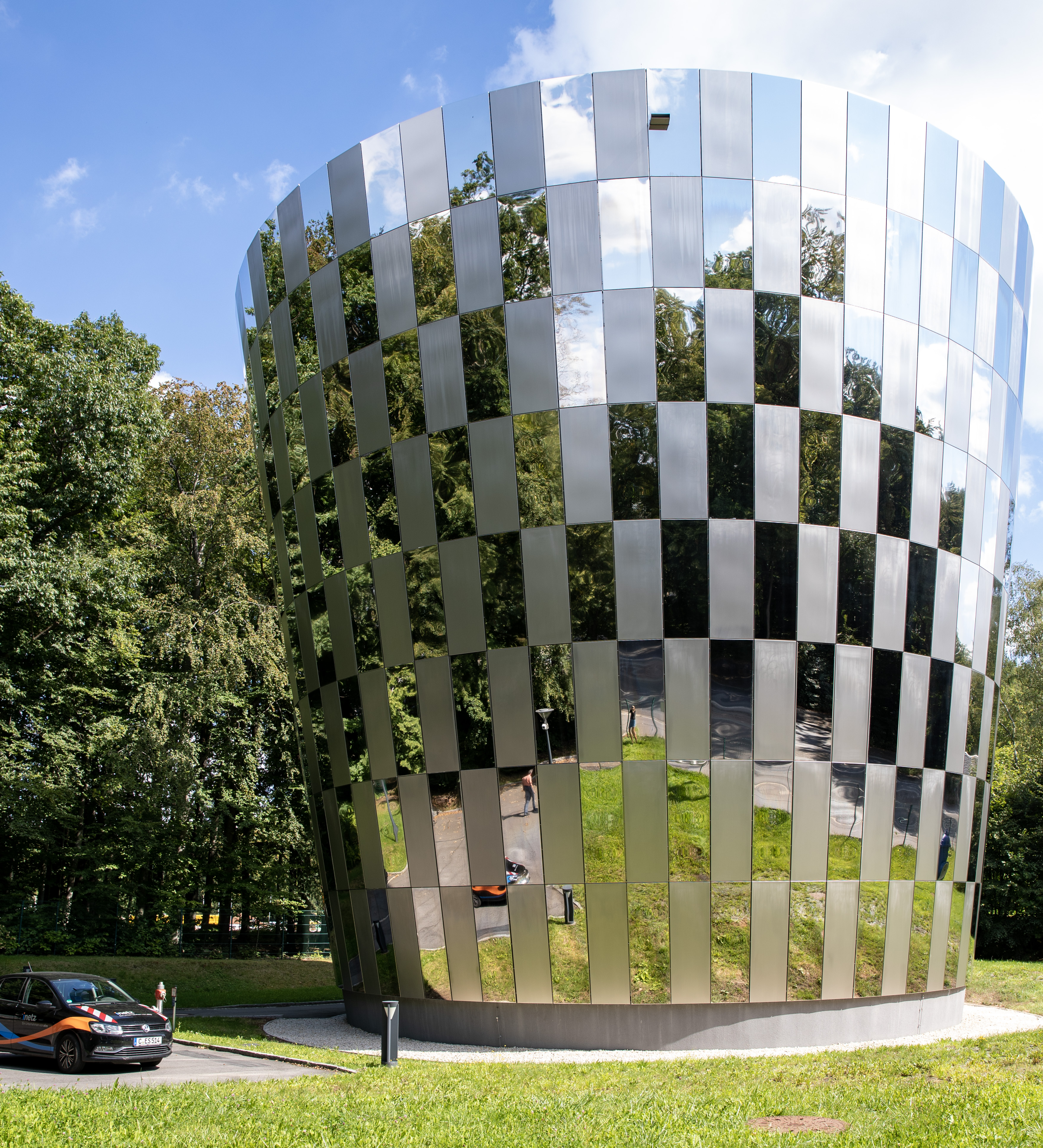 Trinkwasserspeicher mit verspiegelter Fassade, davor steht ein eins Auto